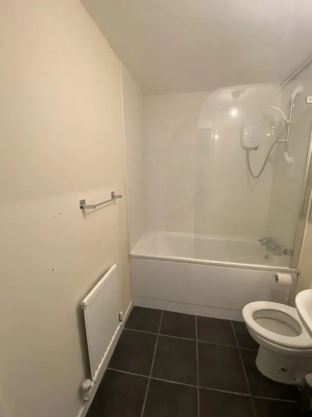 Bathroom with a white bath, tiled surround and shower
