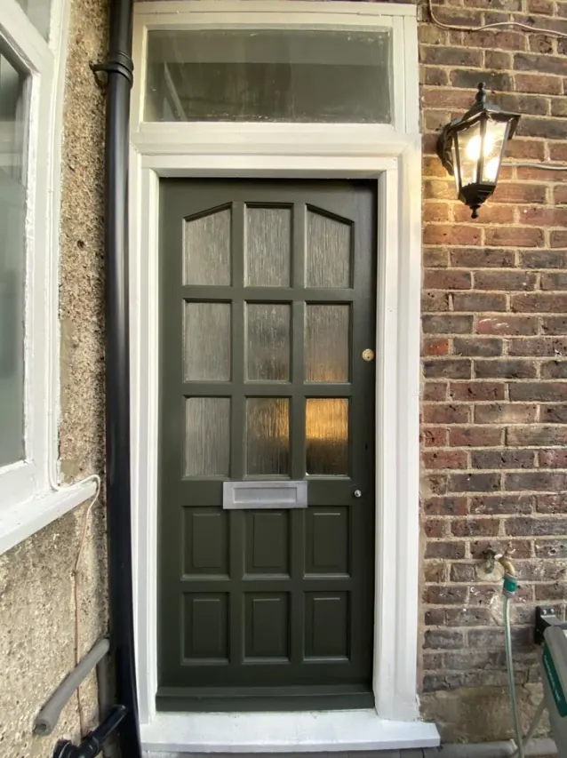 Period front door repainted in deep green with restored glazing